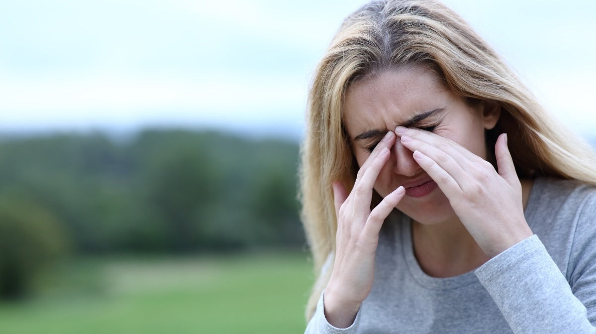 une femme se gratte les yeux qui démangent à l'extérieur
