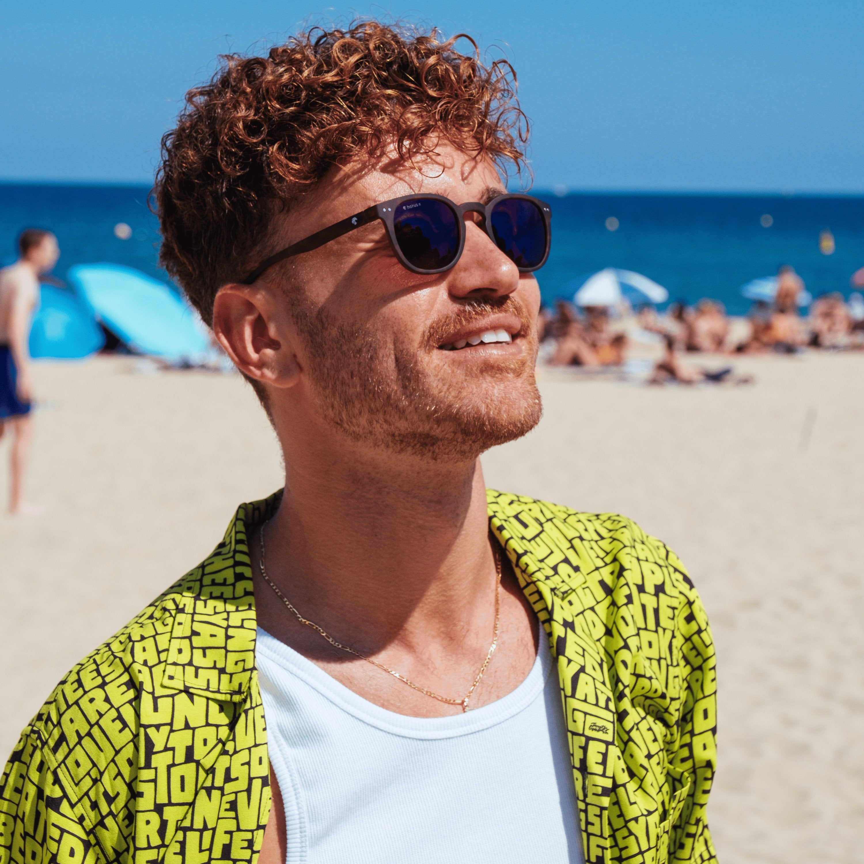 Lucas regarde le ciel avec les lunettes Stockholm marrons solaires à la plage devant l'océan