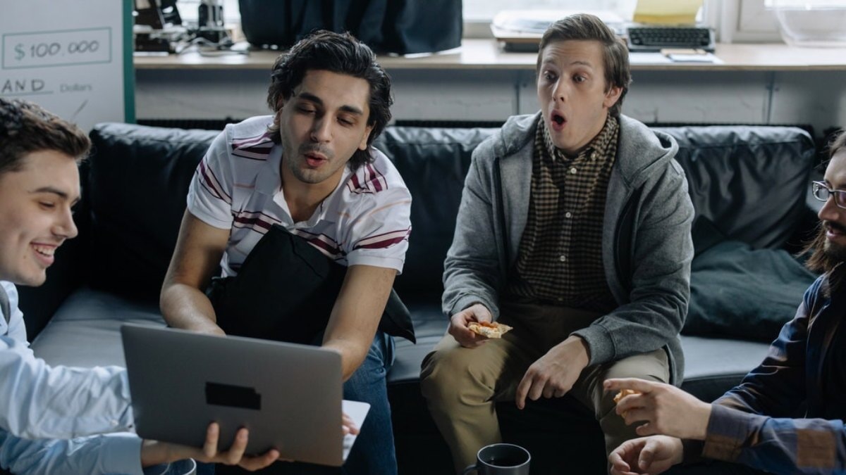 4 hommes regardant un match sur un ordinateur portable
