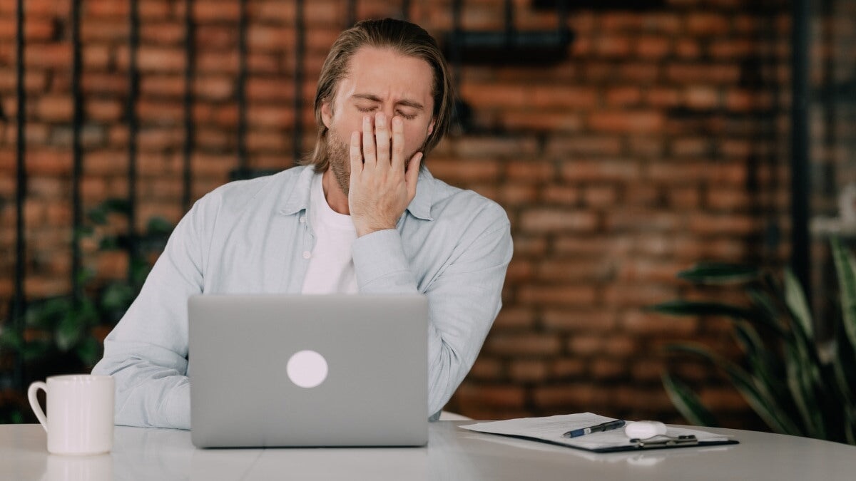Un homme à son bureau bâille assis devant un ordinateur. Concept de privation de sommeil