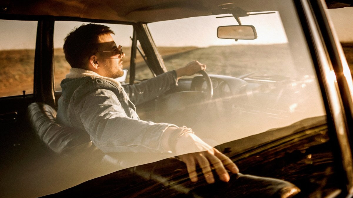 un homme conduisant une voiture au coucher du soleil