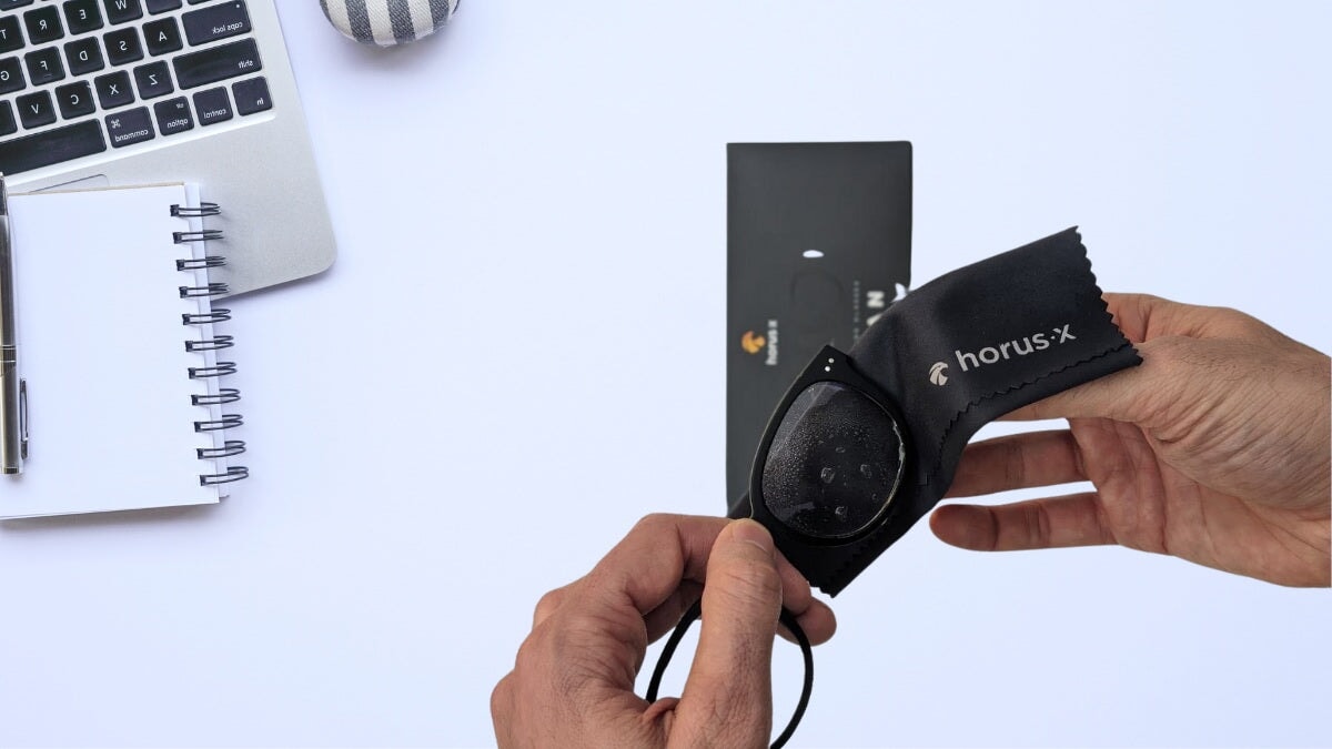 un homme nettoyant ses lunettes horus x avec un tissu en microfibre