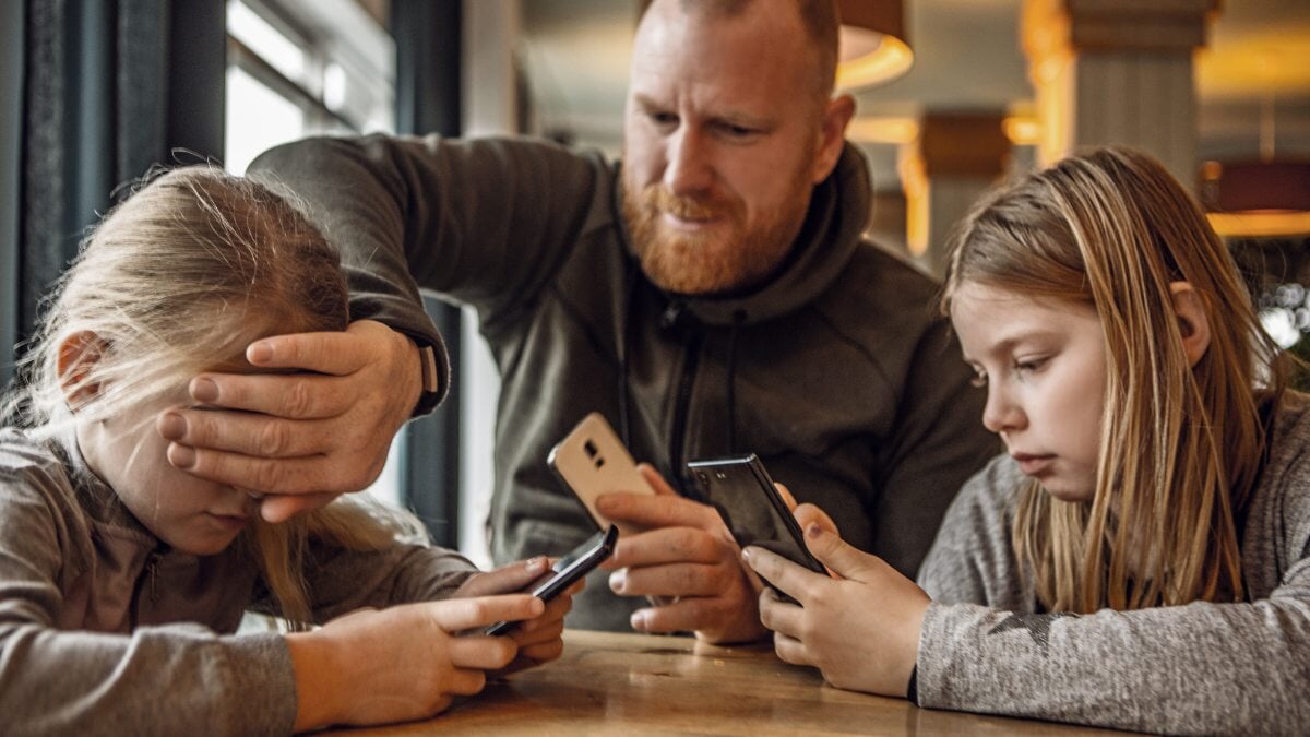 un père essayant de limiter le fuseau horaire de l'écran pour son père et ses filles