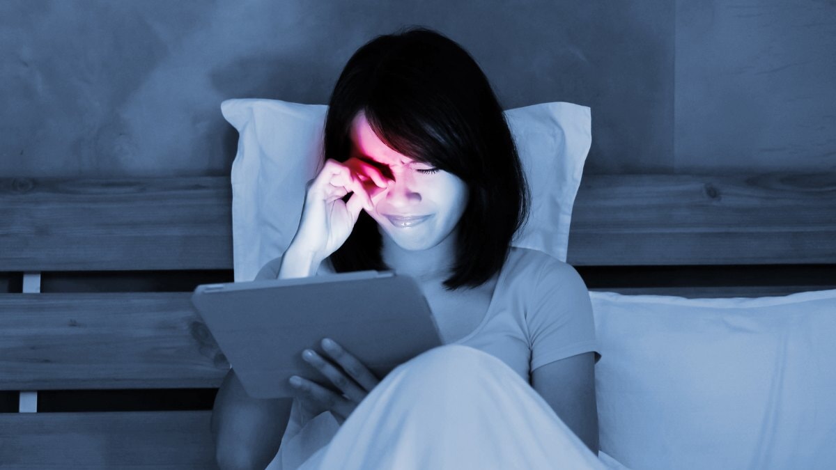 une femme touchant ses yeux fatigués tout en regardant son iPad