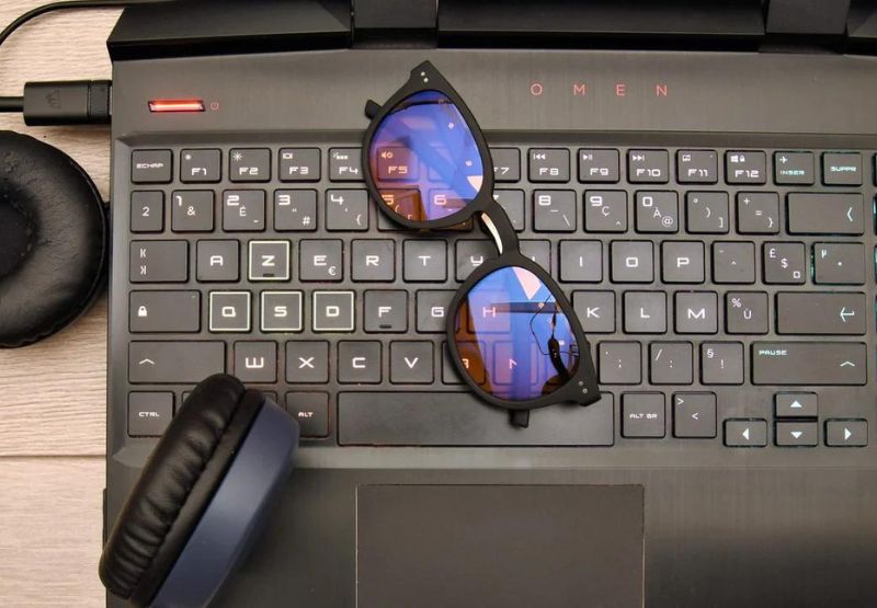 Des lunettes anti lumière bleue ambrées sur un clavier d'ordinateur gaming avec des écouteurs