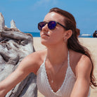 Notre modèle féminin porte les clips on solaires à la plage sous le ciel ensoleillé