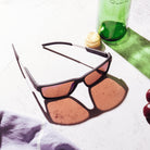 Les One Revo Sun lunettes de soleil sur un comptoir avec divers objets estivaux, bouteille, draps, cerises