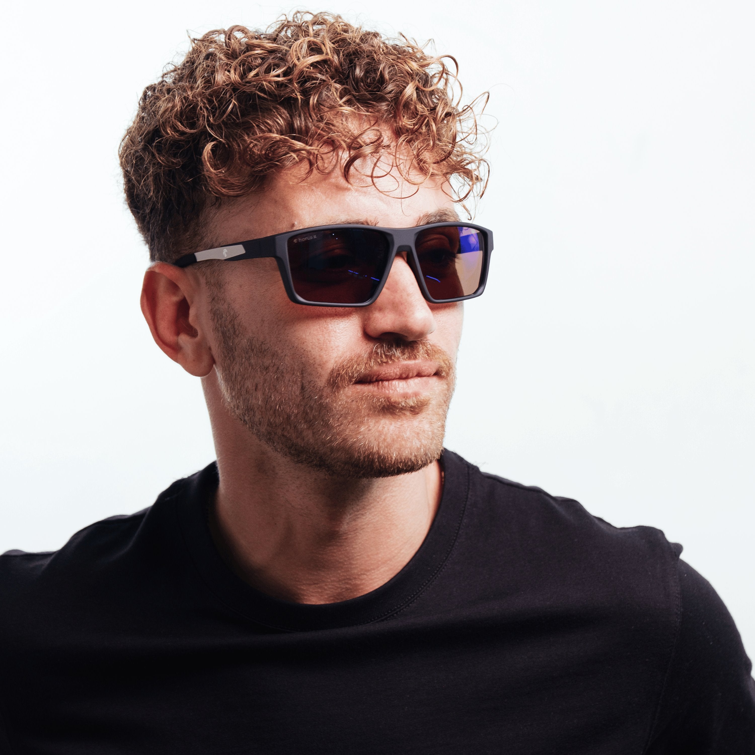 Portrait de lucas de 3/4 avec les lunettes de soleil Horus X Revo One Sun sur fond blanc